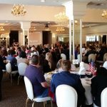 View of the dining room full of people attending the presentation at the luncheon